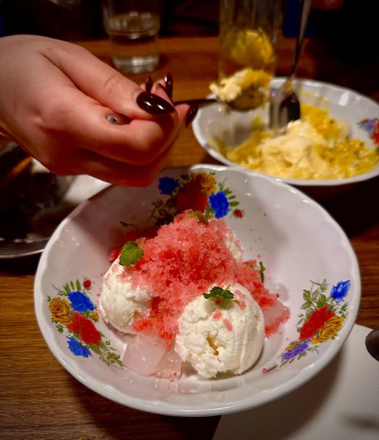 Shaved-ice dessert with ice cream, watermelon granita and mint in a floral bowl