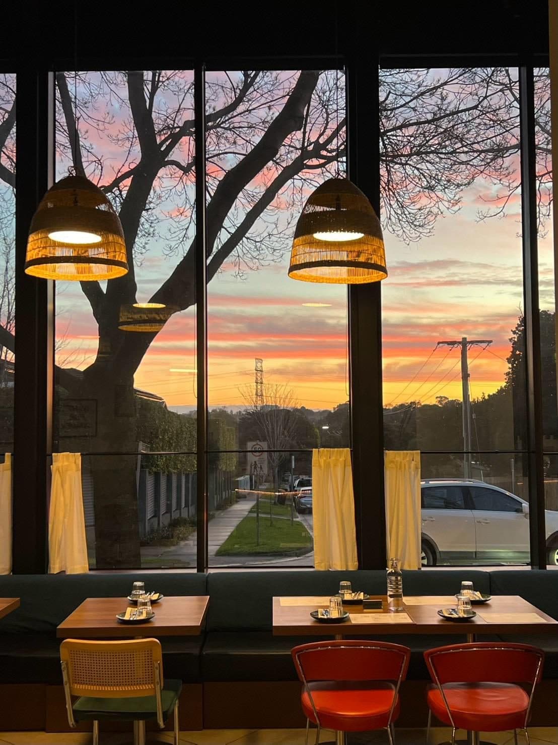 The Rice Club dining room glowing at sunset, pendant lights over the tables