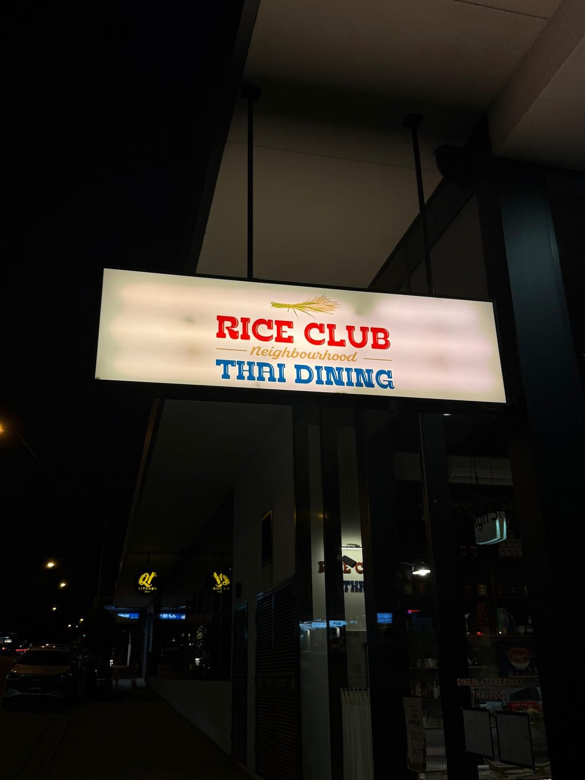The lit Rice Club sign on High Street at night