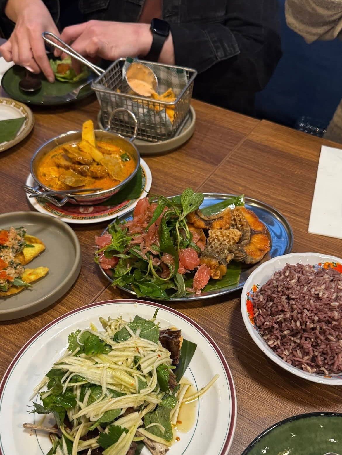 An overhead spread of Thai dishes laid out for sharing