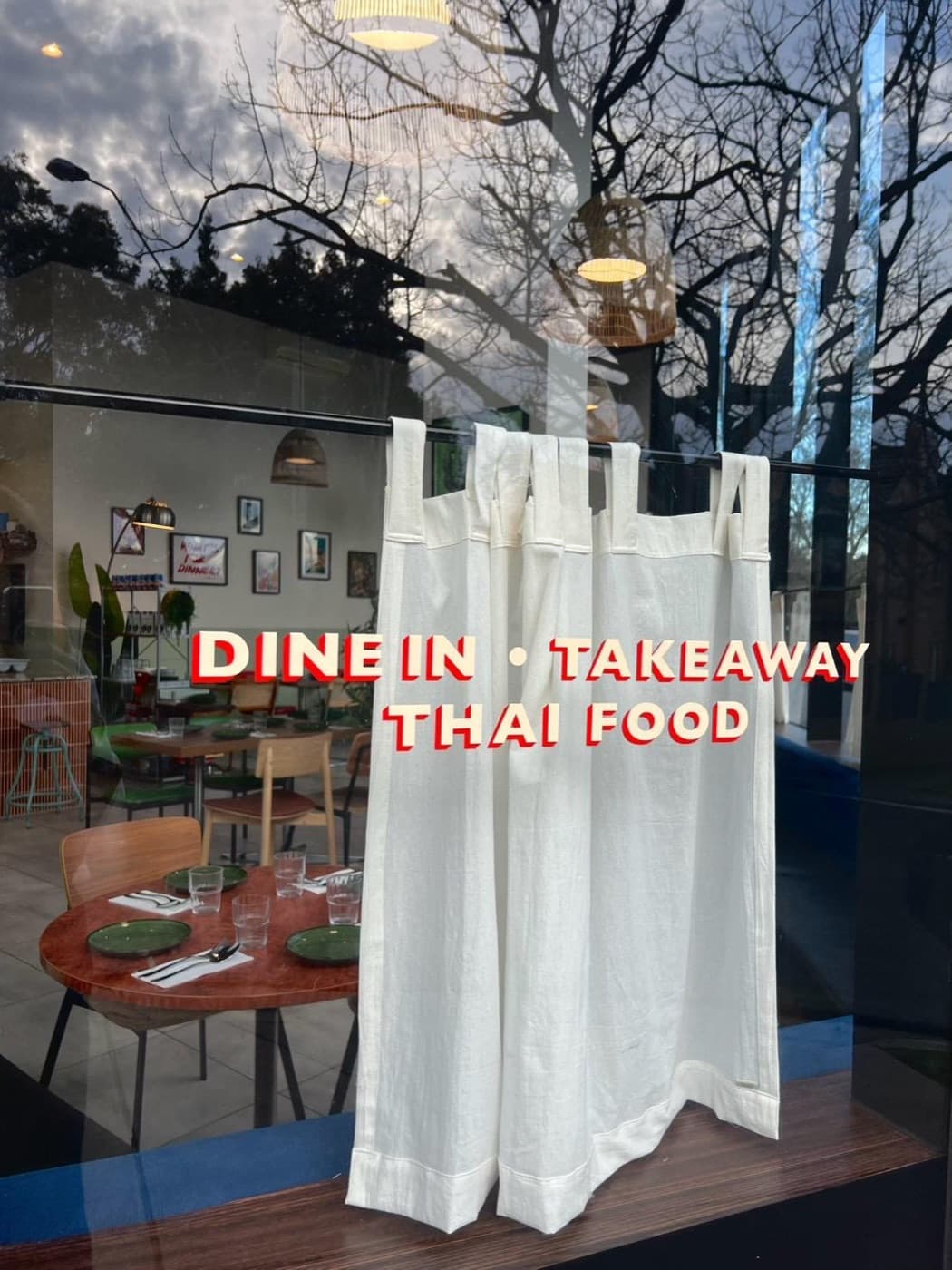Rice Club shopfront at dusk with the red 'Dine in · Takeaway · Thai Food' window decal, the dining room behind the glass